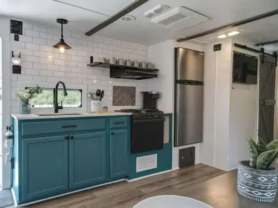a kitchen with blue cabinets and a sink at Wildflower Wanderlust-Glamping st 1885 Farms in Navarre