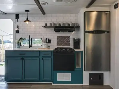 a kitchen with blue cabinets and a stainless steel refrigerator at Wildflower Wanderlust-Glamping st 1885 Farms in Navarre