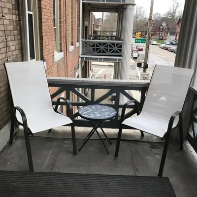 two white chairs and a table on a porch at Big Brick 2 Bedroom apartment in Victorian Village in Columbus