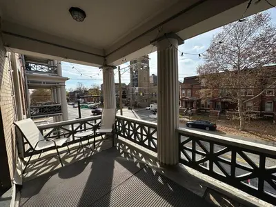 a porch with a chair and a view of a street at Big Brick 2 Bedroom apartment in Victorian Village in Columbus