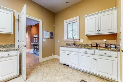 a kitchen with white cabinets and a dining room at The Estate House-Timeless Elegance at 1885 Farms in Navarre