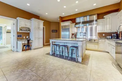 a large kitchen with white cabinets and bar stools at The Estate House-Timeless Elegance at 1885 Farms in Navarre