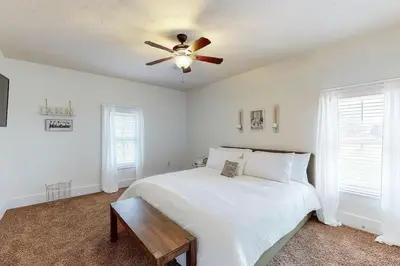 a bedroom with a white bed and a ceiling fan at The Farmhouse at 1885-Where Past Meets Present in Navarre