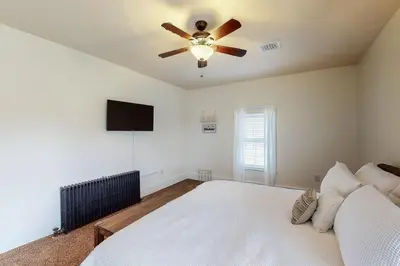 a bedroom with a white bed and a ceiling fan at The Farmhouse at 1885-Where Past Meets Present in Navarre