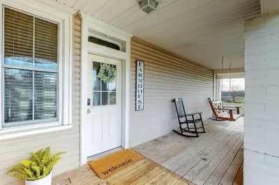 a front porch of a house with a white door at The Farmhouse at 1885-Where Past Meets Present in Navarre