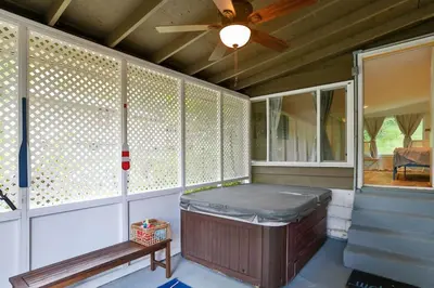 a screened in porch with a hot tub and a ceiling fan at Atwood Breeze-Tranquil Lake Escape in Sherrodsville