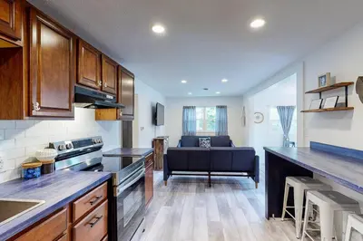 a kitchen with wooden cabinets and a living room with a couch at Atwood Breeze-Tranquil Lake Escape in Sherrodsville