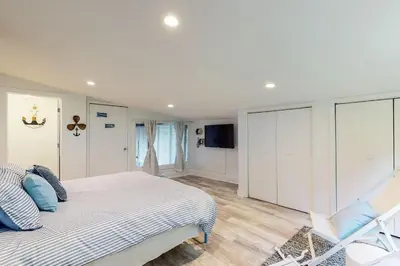 a white bedroom with a bed and a chair at Atwood Breeze-Tranquil Lake Escape in Sherrodsville