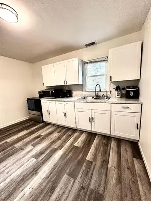 a kitchen with white cabinets and a wooden floor at Cozy Muncie Home Near Downtown in Muncie