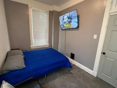 a bedroom with a bed and a tv on the wall at Second floor petite studio private room in Cincinnati