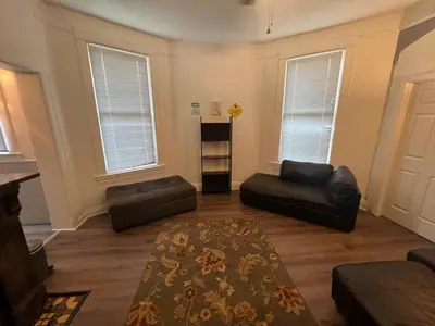 a living room with black leather furniture and windows at Second floor standard studio private room in Cincinnati