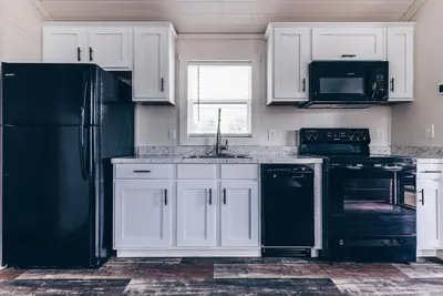 a kitchen with white cabinets and a black refrigerator at Cincinnati Camp Cedar in Mason