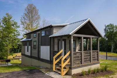 a tiny house with a black roof and a porch at Cincinnati Camp Cedar in Mason