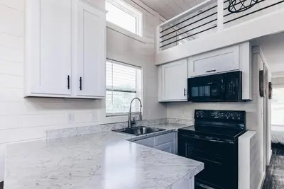 a kitchen with white cabinets and a black appliance at Cincinnati Camp Cedar in Mason