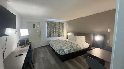 a small hotel room with a bed and a desk at Botkins Motel