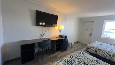 a room with a bed and a desk with a television at Botkins Motel