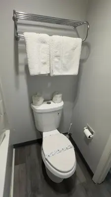 a bathroom with a white toilet and towels at Botkins Motel