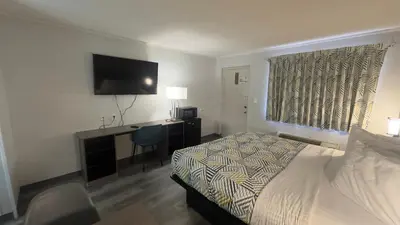 a bedroom with a bed and a desk and a television at Botkins Motel