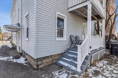 a white house with a porch with a chair on it at Tiny Taco House in Lakewood