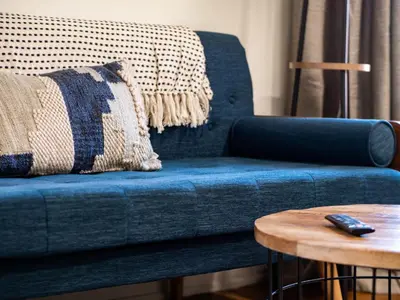 a blue couch with a pillow and a table at Carriage Manor - Sun Soaked 1BR - Close to CCF in Cleveland