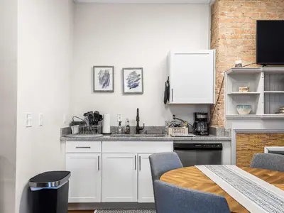 a kitchen with white cabinets and a table at Carriage Manor - Sun Soaked 1BR - Close to CCF in Cleveland