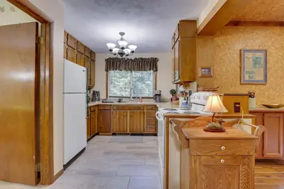 a kitchen with wooden cabinets and a white refrigerator at Peaceful Carrollton Retreat with Deck and Fire Pit! in Carrollton