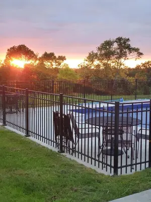 a fence with a table and benches next to a pool at Home for 21 Near Ark - Ensuite Bathrooms - with Pool! in Williamstown