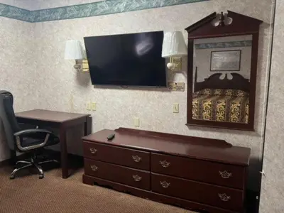 a room with a desk and a dresser and a mirror at Garden Inn in New Castle