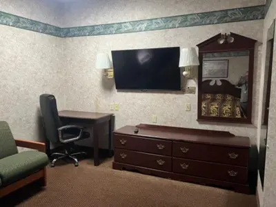 a hotel room with a desk and a dresser and a television at Garden Inn in New Castle