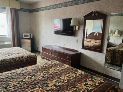 a hotel room with two beds and a mirror at Garden Inn in New Castle