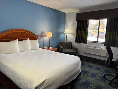 a hotel room with a bed and a chair and a window at South Ridge Inn in North Ridgeville