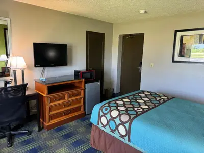 a small hotel room with a bed and a television at South Ridge Inn in North Ridgeville