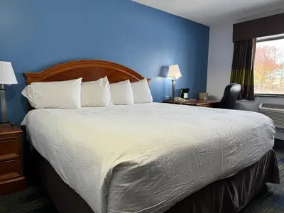 a bedroom with a large bed with a blue wall at South Ridge Inn in North Ridgeville