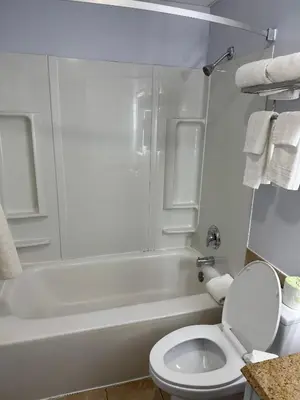 a white bathroom with a toilet and a bath tub at South Ridge Inn in North Ridgeville