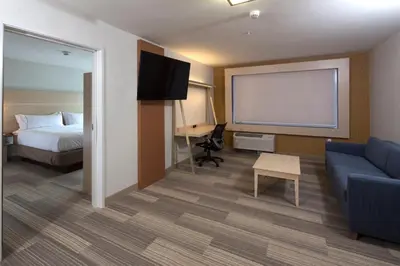 a hotel room with a bed a couch and a screen at Holiday Inn Express & Suites Monroe by IHG in Monroe