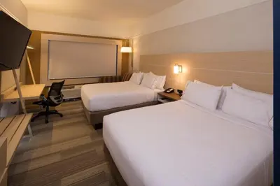 a hotel room with two beds and a projection screen at Holiday Inn Express & Suites Monroe by IHG in Monroe