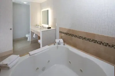 a bathroom with a large tub and a sink at Holiday Inn Express & Suites Monroe by IHG in Monroe