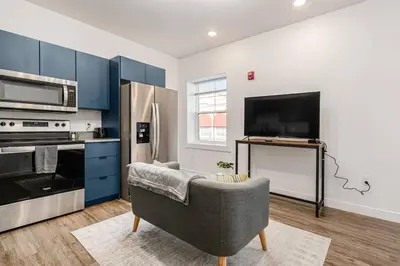a kitchen with blue cabinets and a couch and a refrigerator at Columbus Gem with Pool Table! Pets Welcome! in Columbus