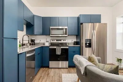 a kitchen with blue cabinets and a stainless steel refrigerator at Columbus Gem with Pool Table! Pets Welcome! in Columbus