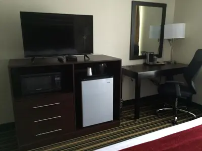 a room with a television and a desk with a mirror at The Inn in Monaca