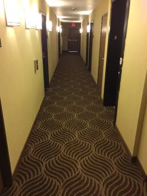 a hallway in a hotel with a carpeted floor at The Inn in Monaca