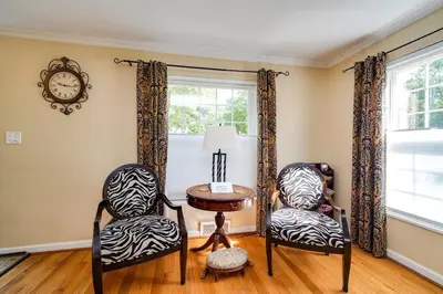 a room with two chairs and a table and a clock at Antique Charm 3BR Gourmet Kitchen & Large Yard in Kettering