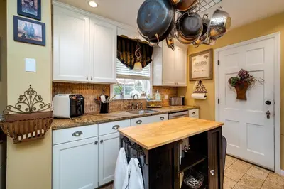 a kitchen with white cabinets and a wooden counter top at Antique Charm 3BR Gourmet Kitchen & Large Yard in Kettering