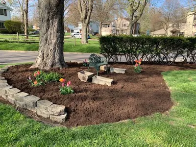 a flower bed around a tree with flowers at Antique Charm 3BR Gourmet Kitchen & Large Yard in Kettering