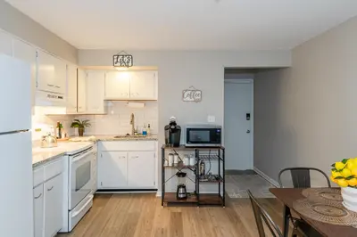 an open kitchen with white cabinets and a table at Modern 2BR Gem Steps to The Greene UD & WPAFB in Kettering