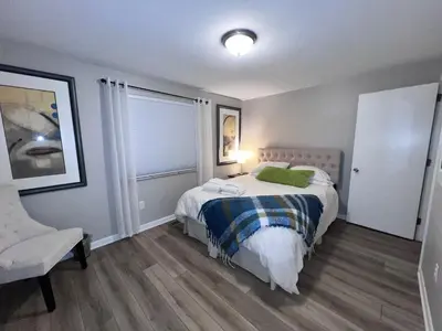 a bedroom with a bed with a green pillow and a chair at Heart Day Deal Holiday Retreat Prime Location in Kettering