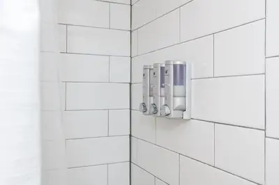 a white tiled bathroom with three soap dispensers at Modern Gem Steps from The Greene UD & WPAFB in Kettering