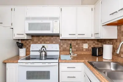 a kitchen with white cabinets and a stove and a sink at Modern Gem Steps from The Greene UD & WPAFB in Kettering