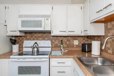 a white kitchen with a stove and a sink at Modern Gem Steps from The Greene UD & WPAFB in Kettering
