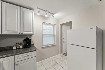a kitchen with white cabinets and a white refrigerator at Close to The Greene, Escape Kalm Retreat in Kettering